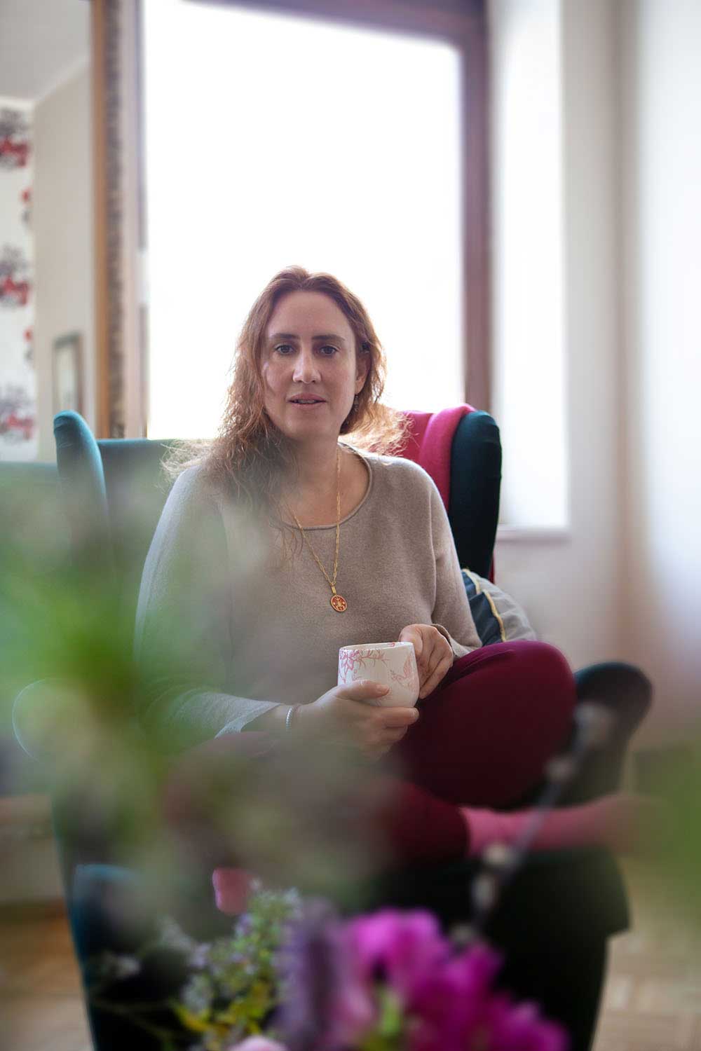 IMG_5295- Die zertifizierte Human-Design-Consultanterin Janina Dahse sitzt entspannt in einem Sessel und hält eine Tasse in der Hand.